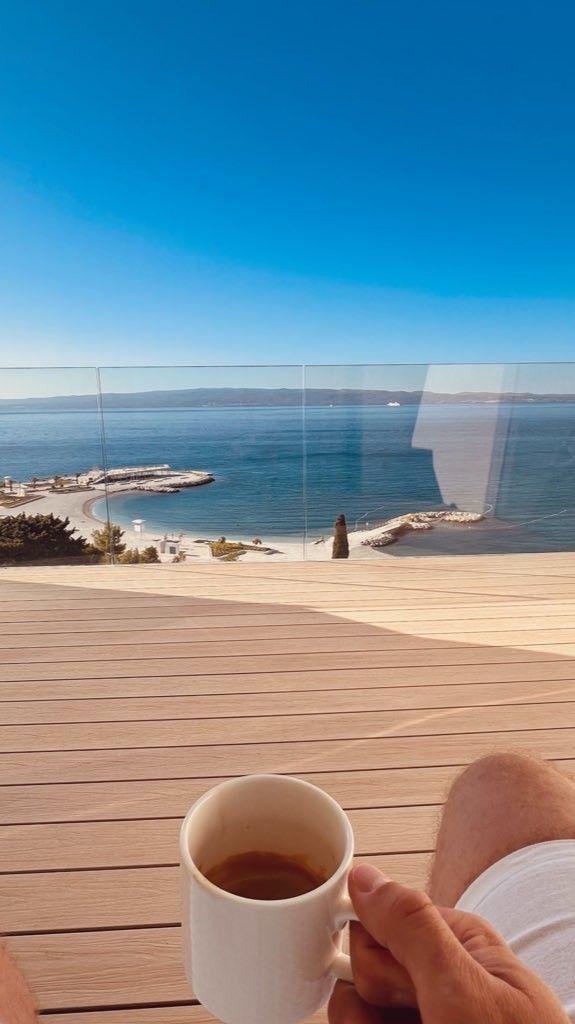 A cup of coffee on a wooden deck by the sea